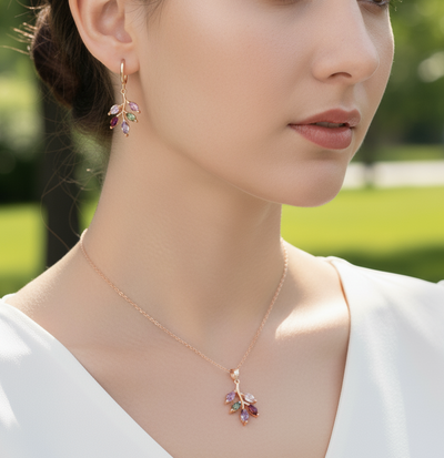 Close-up of a woman wearing a necklace and earrings with a blurred green outdoor background